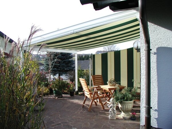 Überdachte Terrasse mit Markise, Holzmöbeln und Pflanzen für gemütliche Gartenmomente.