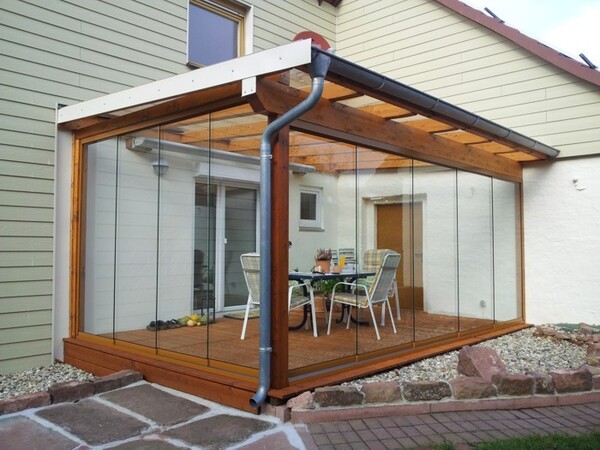 Moderner Wintergarten mit Glaswänden und Holzkonstruktion an einem Einfamilienhaus.